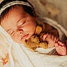 newborn, baby, sleeping, blanket, teddy_bear, headband, infant, cute, soft_texture, wrapped, peaceful, close_up, tiny_feet, portrait, indoors, warm_lighting, cozy, child, resting, adorable