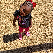 Catalaya joined the competition — help win amazing prizes! black_tshirt, braided_hair, casual_clothing, child, cute, daylight, fun, girl, happy, outdoor, person, pink_shoes, pink_shorts, playground, red_bow, shadow, smile, standing, sunny, wood_chips