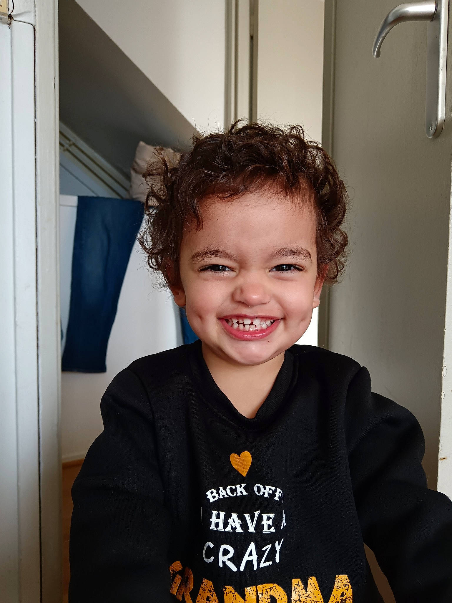 David participe au concours pour gagner de l'argent avec cette photo : child, door, face, flash_photography, fun, happy, hoodie, joy, laugh, logo, person, portrait_photography, room, sitting, sleeve, smile, standing, t_shirt, toddler, top