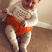 Enzo is registered to the contest to win money with this photo: baby, carpet, child, costume, cute, festive, halloween, holiday, indoor, infant, leggings, orange_hat, person, playful, pumpkin, shadow, smiling, socks, wall, white_clothing