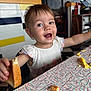 toddler, child, bread, food, table, smile, happy, mealtime, diner, scrambled_eggs, crumbs, white_shirt, indoor, person, face, cute, expression, colorful, highchair, eating