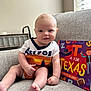 baby, child, smile, astros, onesie, couch, gray, book, colorful, illustration, indoor, window, light, cute, sitting, foot, hand, wall, happy, portrait