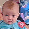 Leanna is registered to the contest to win money with this photo: baby, infant, face, expression, blue_shirt, heart_doodle, television, man, blurred_background, indoor, person, sign, motivational_text, head, skin, eyes, ear, clothing, portrait, closeup