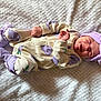 baby, newborn, sleeping, onesie, purple, headband, bow, socks, blanket, soft_texture, clothing, infant, cute, resting, portrait, child, cozy, indoors, peaceful, closeup