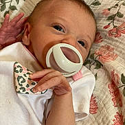 Paislee joined the competition — help win amazing prizes! baby, newborn, pacifier, onesie, hand, face, infant, blanket, floral_pattern, sleepwear, cute, close_up, skin, resting, pink, white, small_hands, lying_down, young_child, portrait