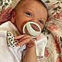 baby, newborn, pacifier, onesie, hand, face, infant, blanket, floral_pattern, sleepwear, cute, close_up, skin, resting, pink, white, small_hands, lying_down, young_child, portrait