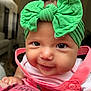 Peyton is registered to the contest to win money with this photo: baby, child, face, smile, headwrap, green_bow, pink_clothing, drool, close_up, indoor, person, infant, cute, portrait, warm_lighting, furniture, soft_focus, happy, young_child, holding