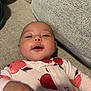 Peyton joined the competition — help win amazing prizes! baby, infant, child, onesie, apple_pattern, couch, fabric, texture, hand, face, cute, smiling, indoor, relaxing, young, portrait, clothing, soft, person, lying_down