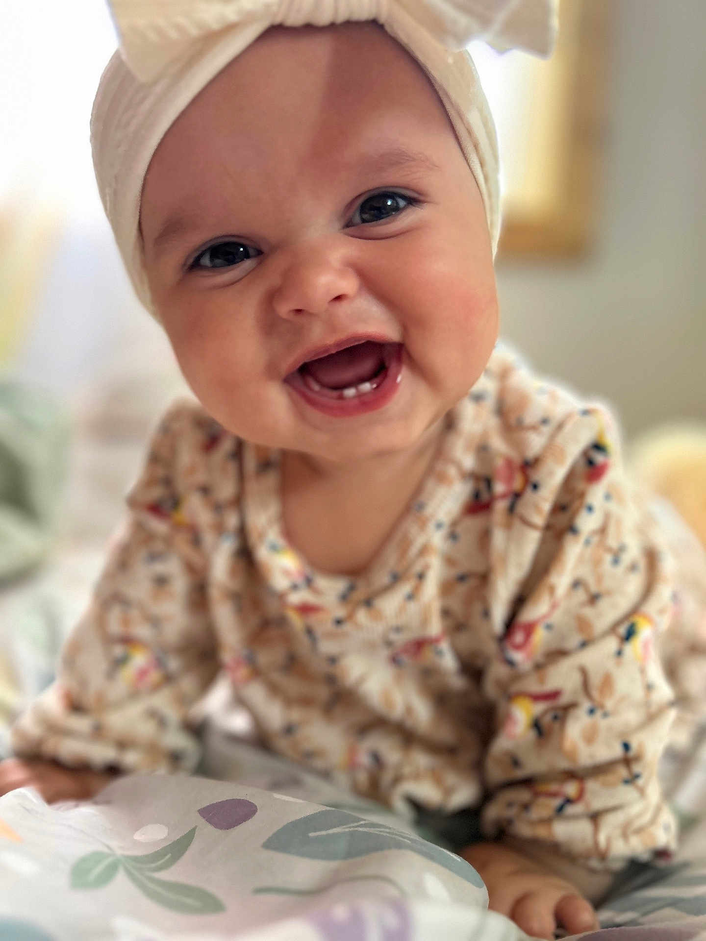 Estrella is registered to the contest to win money with this photo: baby, smiling, face, headband, bow, eyes, sweater, patterned_clothing, infant, cute, happy, portrait, child, indoors, blanket, hand, closeup, cheerful, soft_light, young