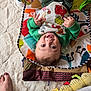 Antonio joined the competition — help win amazing prizes! baby, child, play_mat, toy, smiling, happy, indoor, clothing, face, person, colorful, blanket, foot, nail_polish, green_sweater, patterned_toy, soft_surface, head, looking_up, cute