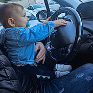 Giovanni participe au concours pour gagner de l'argent avec cette photo : adult, baby, car_interior, car_seat, casual_clothing, child, denim_jacket, hand, jeans, nature, outdoor, pacifier, parking_lot, person, shoe, side_mirror, steering_wheel, toddler, vehicle, window