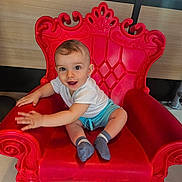 Giovanni participe au concours pour gagner de l'argent avec cette photo : baby, child, smiling, red_chair, indoor, cute, sitting, happy, playful, person, shorts, white_shirt, socks, furniture, decorative_chair, expression, young_child, portrait, hands, eyes