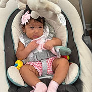 Brianna is registered to the contest to win money with this photo: baby, infant, child, car_seat, plush_toys, stuffed_animals, pink_bow, pink_socks, pink_clothing, sitting, indoors, portrait, face, dark_hair, wide_eyes, toy_mobile, seat_belt, harness, smiling, family_photo