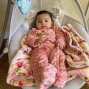 Angela is registered to the contest to win money with this photo: baby, pink_onesie, blanket, baby_swing, toys, floral_pattern, carpet, indoor, child, cute, infant, comfort, relaxing, plush, smiling, face, person, warm, soft, home
