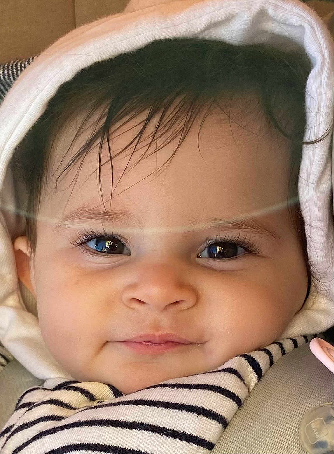 Hind participe au concours pour gagner de l'argent avec cette photo : baby, child, face, hood, striped_clothing, closeup, eyelashes, cute, infant, person, portrait, soft_light, car_seat, pacifier, smile, skin, hair, clothing, warm, indoors