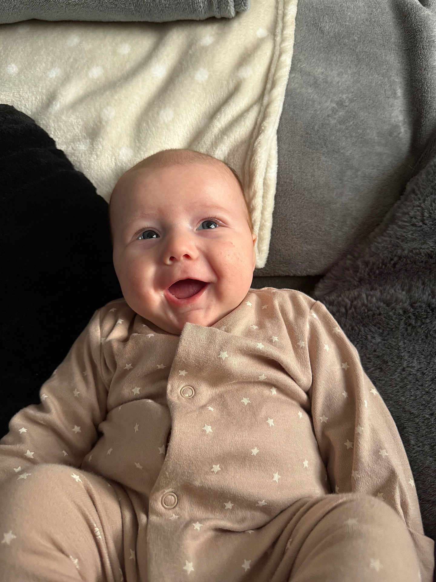 Noah-James joined the competition — help win amazing prizes! baby, infant, smile, onesie, star_pattern, blanket, cozy, happy, cute, child, soft_texture, face, lying_down, indoors, apparel, person, skin, head, expression, comfort