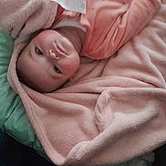 Inaya participe au concours pour gagner de l'argent avec cette photo : baby, blanket, pink, child, face, lying_down, cushion, indoor, soft_texture, infant, clothing, portrait, messaging_app, screenshot, cozy, young_child, looking, wrapped, cute, resting