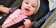 Addelina joined the competition — help win amazing prizes! baby, infant, stroller, headband, bow, pink_clothing, smiling, happy, child, seatbelt, black_stroller, indoor, wooden_floor, cute, person, portrait, young_child, baby_girl, baby_clothes, baby_smile