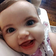Addelina joined the competition — help win amazing prizes! baby, closeup, smiling, face, child, indoor, couch, furniture, floor, wooden_floor, clothing, patterned_clothing, happy, portrait, person, infant, head, eyes, mouth, skin