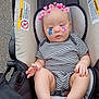 baby, infant, stroller, striped_clothing, child, cute, face_stickers, hearts, flowers, cartoon_characters, outdoor, pavement, warning_labels, legs, feet, hands, seat, safety, person, casual
