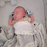 Paisley is registered to the contest to win money with this photo: newborn, baby, sleeping, blanket, mittens, crib, plush_toy, soft, pastel, cozy, infant, bed, cute, peaceful, resting, child, person, indoor, comfort, toddler