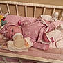 baby, bottle, crib, diaper, pink_outfit, headband, socks, baby_supplies, blanket, infant, sleeping_area, feeding, child, bed, soft_toys, cute, indoors, resting, newborn, cozy