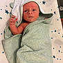 baby, infant, towel, hooded_towel, wrapped, face, hand, blue_eyes, star_pattern, bed, blanket, child, newborn, cute, skin, expression, soft, indoor, person, resting