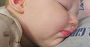 Dean is registered to the contest to win money with this photo: baby, casual_clothing, child, close_up, comfort, cozy, cute, face, hand, indoor, infant, peaceful, person, portrait, relaxation, rest, skin, sleep, sleeping, soft_lighting