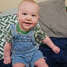 baby, blue_eyes, child, couch, cute, denim_overalls, fabric, face, foot, green_shirt, hand, happy, indoor, infant, pillow, plush_pillow, short_hair, sitting, skin, smiling