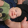 arm, baby, black_blanket, blanket, blue_blanket, child, cute, face, green_shirt, hand, happy, indoor, infant, lying_down, mickey_mouse, person, portrait, reaching, smile, young_child