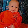 baby, blanket, child, colorful_background, cozy, cute, digital_overlay, early_morning, face, hand, happy, indoors, infant, lying_down, orange_clothing, portrait, smiling, soft_texture, warm_colors, young