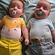 Charli participe au concours pour gagner de l'argent avec cette photo : baby, infant, pacifier, bed, clothing, shorts, cute, face, lying_down, two_babies, child, adorable, toddler, yellow_shirt, blue_shirt, denim_shorts, soft_bed, holding_hands, closeup, indoors