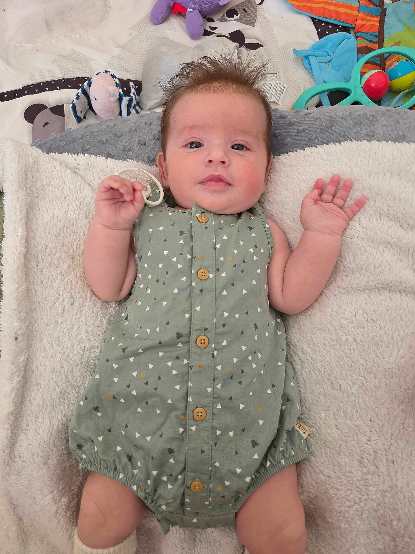 Andréa a rejoint le concours — aidez-le/la à gagner de superbes lots ! baby, infant, romper, blanket, soft_texture, pacifier, toy, colorful, patterned_clothing, cute, lying_down, small_hands, buttons, toddler, indoor, child, playmat, plush_toy, casual, portrait