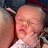 adult, arm, baby, blanket, child, close_up, cozy, cuddling, face, family, hand, indoor, infant, newborn, pajamas, peaceful, pink_clothing, portrait, sleeping, tattoo