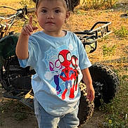 Mariella joined the competition — help win amazing prizes! toddler, child, outdoor, person, jeans, tshirt, spiderman, sneakers, pigtails, dirt_bike, fence, sunlight, dirt, grass, earrings, headband, expression, standing, pointing, daytime