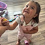 Mariella is registered to the contest to win money with this photo: barefoot, casual_clothing, child, cute, earrings, flooring, girl, holding_hand, home, indoor, interaction, looking_up, person, pink_overalls, play, short_sleeve, smiling, toy, wooden_floor, young_child