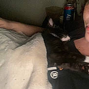 Yara And Kila is registered to the contest to win money with this photo: cat, person, blanket, indoor, sleeping, black_and_white_cat, snuggling, cozy, dim_lighting, close_up, resting, human_arm, tshirt, sitting, relaxing, fur, pet, nighttime, comfort, face_partial