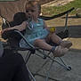 toddler, child, pacifier, chair, outdoor, sunlight, dress, toy, footwear, concrete, fence, tree, shadow, grass, relaxing, play, person, casual, summer, nature