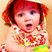 Evelyn joined the competition — help win amazing prizes! baby, child, hat, floral, dress, colorful, toy, green, yellow, surprised, blue_eyes, cute, infant, portrait, sitting, closeup, skin, face, expression, indoors