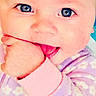 Evelyn joined the competition — help win amazing prizes! baby, close_up, face, blue_eyes, hand, fist, chewing, pink_cuff, purple_clothing, floral_pattern, infant, cute, skin, child, portrait, indoors, soft_texture, expression, young, person