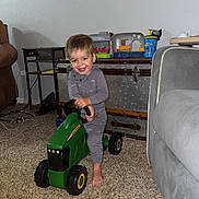 Easton joined the competition — help win amazing prizes! toddler, child, toy, tractor, indoor, carpet, pajamas, smiling, play, furniture, living_room, table, cup, trunk, foot, face, person, happy, playtime, home