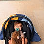 Easton joined the competition — help win amazing prizes! toddler, child, car_seat, pacifier, teddy_bear, stuffed_animal, blanket, barefoot, smiling, outdoor, grass, concrete, toy, happy, person, cute, baby, infant, seat, relaxing