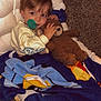 child, teddy_bear, blanket, pacifier, chair, carpet, indoor, cute, cozy, sleepwear, toy, smiling, person, young_child, snuggling, plush, comfort, home, relaxing, portrait