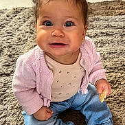 Ayla participe au concours pour gagner de l'argent avec cette photo : baby, child, smiling, sitting, indoor, carpet, pink_sweater, jeans, barefoot, snack, curly_hair, cute, happy, portrait, toddler, playful, small_hair_tie, floor, casual_clothing, bright_eyes