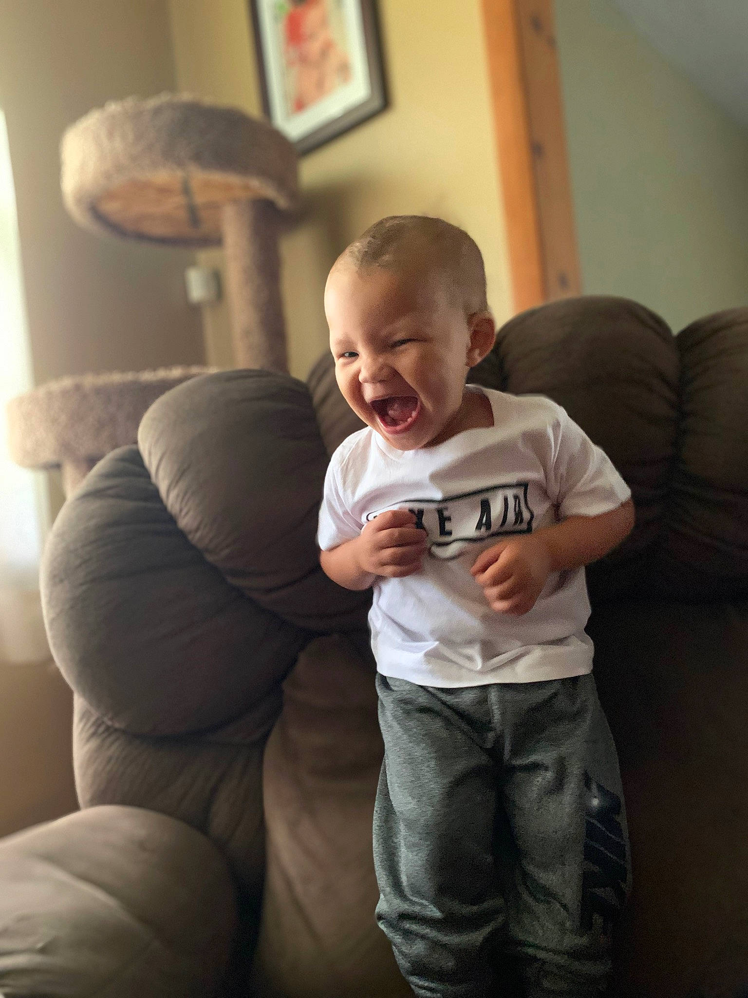 Demetrius is registered to the contest to win money with this photo: cheek, comfort, elbow, finger, floor, flooring, fun, hair, hairstyle, knee, living_room, mouth, person, picture_frame, sleeve, smile, thigh, thumb, toddler, vertebrate