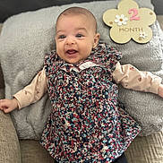 Lucianna participe au concours pour gagner de l'argent avec cette photo : baby, infant, smile, face, pillow, dress, floral_pattern, black_leggings, couch, happy, child, portrait, indoor, cute, 2_month, flower_sign, lying_down, soft_texture, young, person