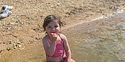 Bella participe au concours pour gagner de l'argent avec cette photo : child, water, swimsuit, beach, rocks, sunlight, smile, sitting, outdoor, nature, summer, playful, small, person, shallow_water, barefoot, legs, happy, daytime, recreation