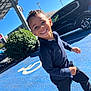 Aron participe au concours pour gagner de l'argent avec cette photo : child, boy, smiling, running, outdoor, parking_lot, handicapped_spot, car, blue_shoes, curly_hair, sunny_day, black_car, casual_clothing, joyful, happy, person, toddler, daylight, asphalt, urban