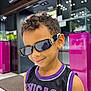 child, boy, sunglasses, smile, curly_hair, earring, sleeveless_shirt, jersey, chicago, indoor, store, display_case, modern, lighting, fashion, portrait, casual, cool, person, shopping