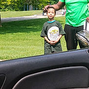 Prince Xaivier joined the competition — help win amazing prizes! child, adult, man, boy, green_shirt, tshirt, outdoor, park, grass, trees, daylight, car_door, road, standing, people, casual_clothing, nature, summer, portrait, family